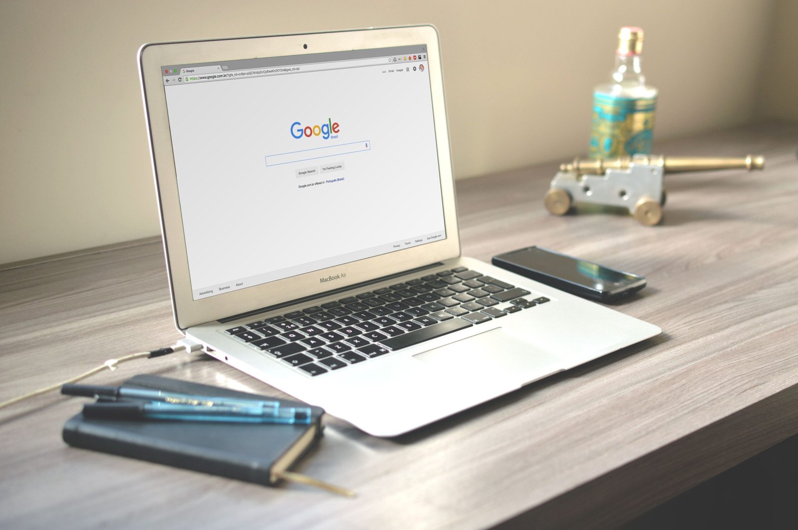Laptop met de Google-zoekpagina op een bureau, naast een smartphone en notitieboek
